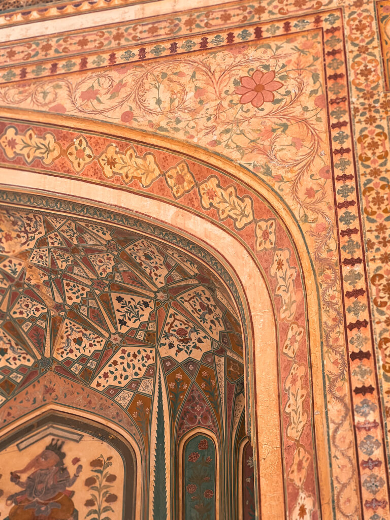 Ornate wall with intricate floral patterns and geometric designs in warm earth tones, conveying a rich, historical ambiance.