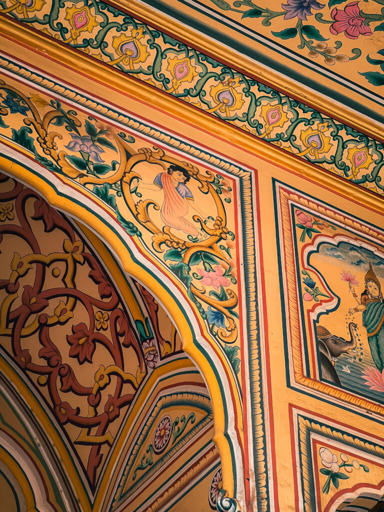 Ornate archway with intricate floral and geometric patterns in vibrant yellow, orange, and green hues. Traditional India and Pakistan decorative artwork evokes cultural richness.